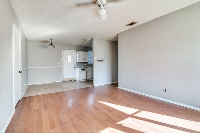 unfurnished living room with a textured ceiling, ceiling fan, and light hardwood / wood-style floors