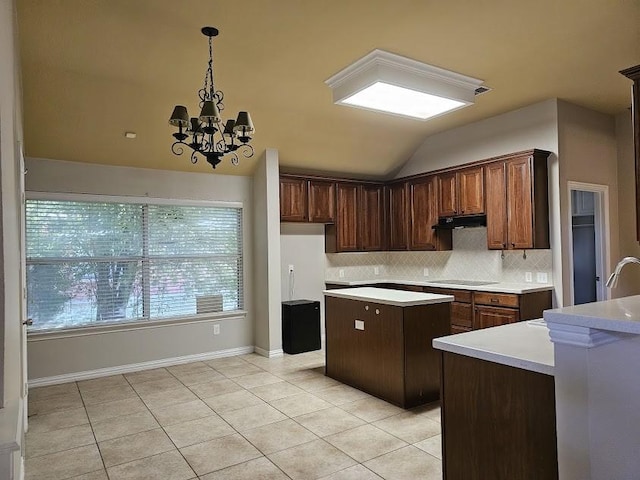 kitchen with an inviting chandelier, light tile patterned flooring, backsplash, a kitchen island, and black electric stovetop