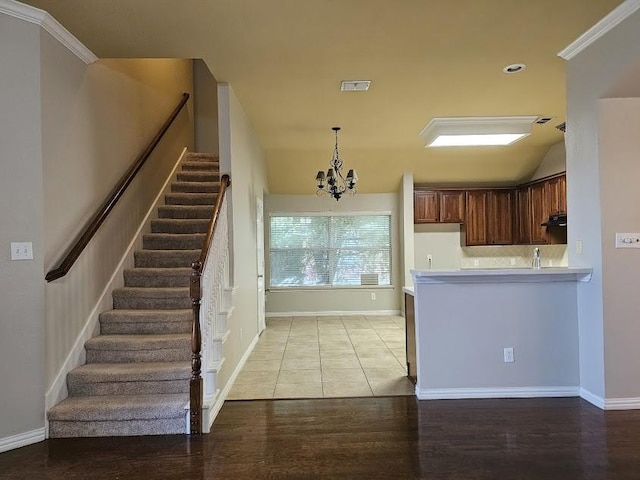 kitchen with decorative light fixtures, ornamental molding, light wood-type flooring, kitchen peninsula, and a chandelier