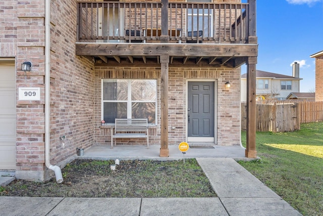 property entrance featuring a balcony and a lawn