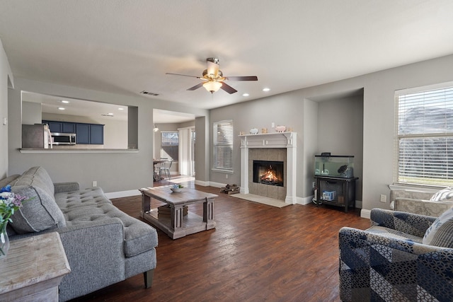 living room with a tile fireplace, ceiling fan, and dark hardwood / wood-style floors