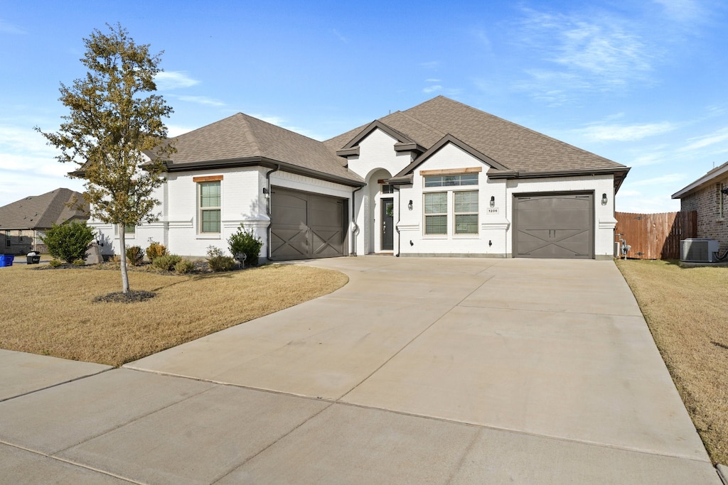 view of front of property with central AC unit, a front lawn, and a garage