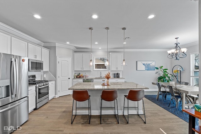 kitchen featuring stainless steel appliances, white cabinets, a center island, decorative backsplash, and hanging light fixtures