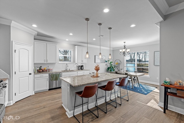 kitchen with pendant lighting, a breakfast bar, a kitchen island, white cabinetry, and appliances with stainless steel finishes