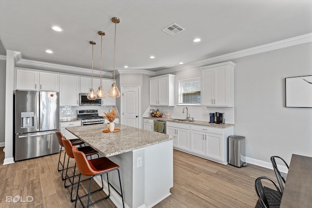 kitchen featuring pendant lighting, a center island, white cabinetry, appliances with stainless steel finishes, and sink