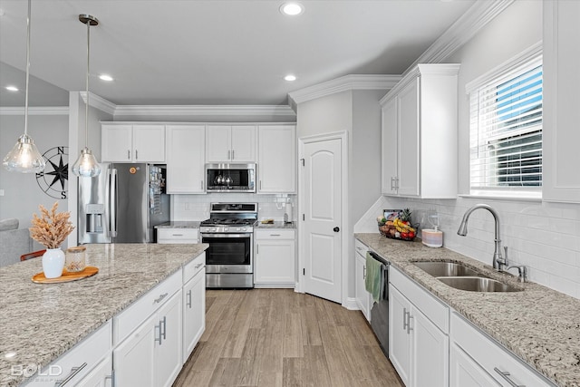 kitchen featuring appliances with stainless steel finishes, pendant lighting, light stone counters, sink, and white cabinetry