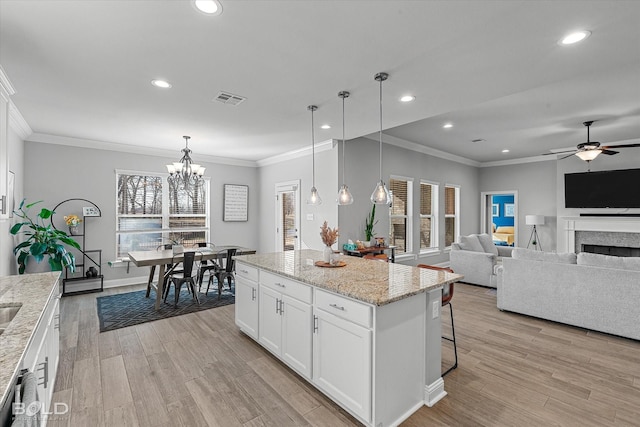 kitchen featuring a center island, white cabinetry, decorative light fixtures, and ceiling fan with notable chandelier