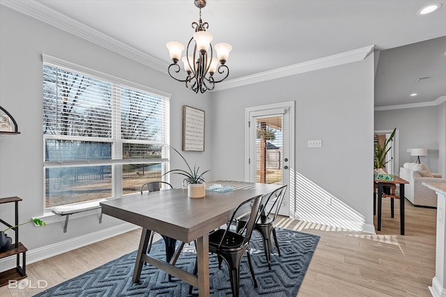 dining area with light hardwood / wood-style floors, ornamental molding, and a chandelier