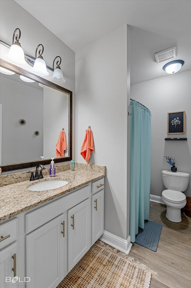 bathroom with toilet, vanity, hardwood / wood-style floors, and curtained shower