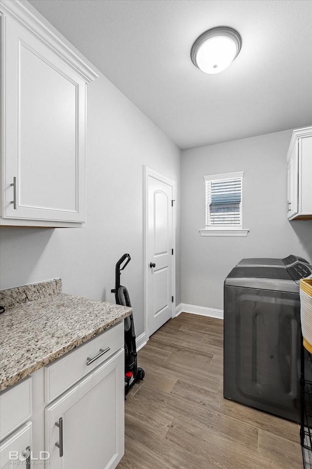 clothes washing area featuring light wood-type flooring, cabinets, and separate washer and dryer