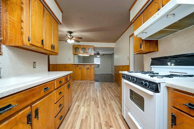 kitchen with light hardwood / wood-style floors, white range with gas stovetop, ceiling fan, sink, and backsplash