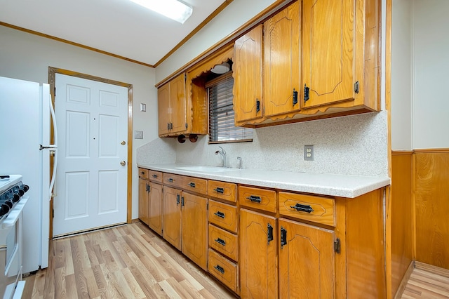 kitchen with sink, white range, ornamental molding, light hardwood / wood-style flooring, and backsplash