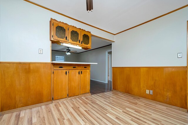 kitchen featuring kitchen peninsula, ceiling fan, crown molding, and light hardwood / wood-style flooring