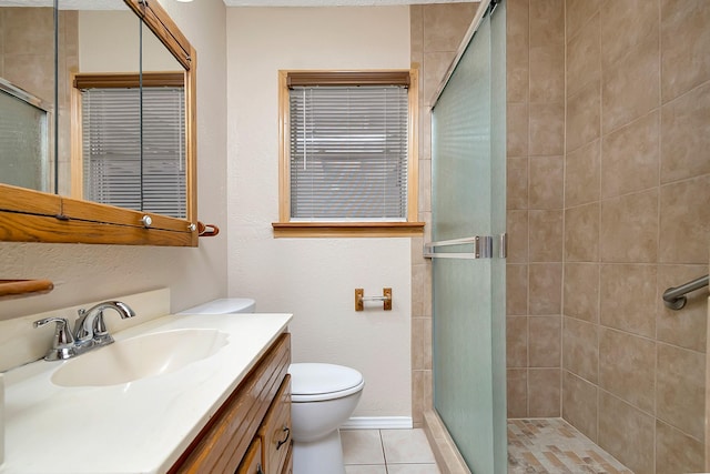 bathroom featuring toilet, vanity, tile patterned floors, and a shower with shower door