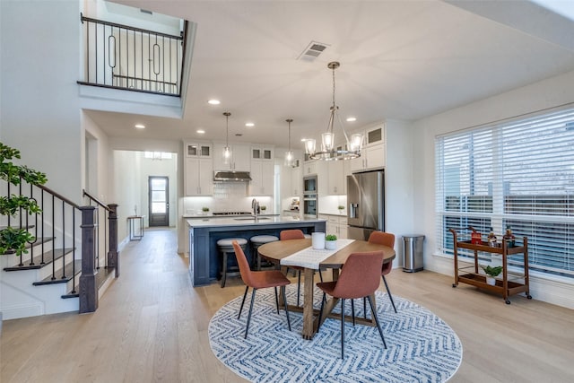 dining room featuring a notable chandelier, light hardwood / wood-style flooring, a wealth of natural light, and sink