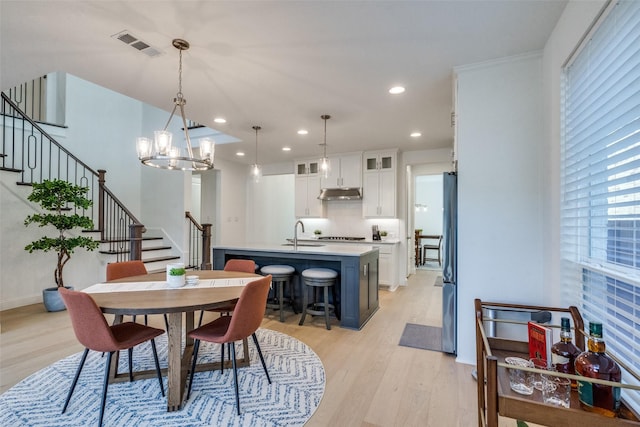 dining room featuring sink, a chandelier, light hardwood / wood-style floors, and crown molding