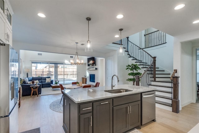 kitchen featuring appliances with stainless steel finishes, light hardwood / wood-style floors, light stone countertops, sink, and white cabinetry