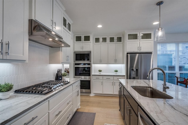 kitchen with white cabinets, stainless steel appliances, sink, decorative light fixtures, and backsplash