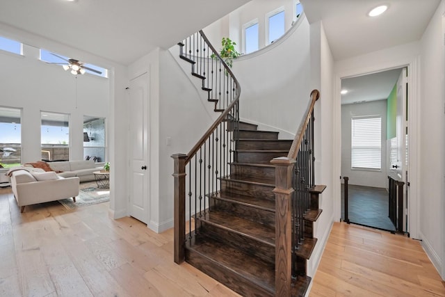 stairway with ceiling fan, a healthy amount of sunlight, and wood-type flooring