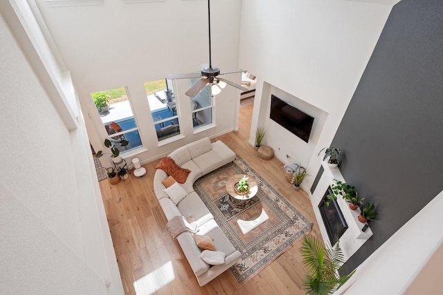 living room with a high ceiling, wood-type flooring, and ceiling fan