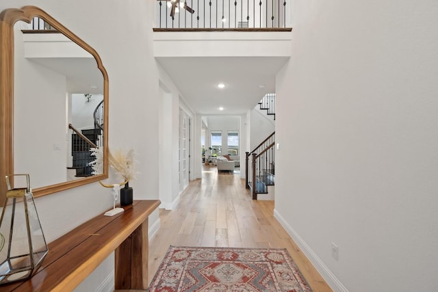 entryway with a towering ceiling and light wood-type flooring