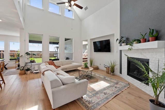 living room with a high ceiling, light wood-type flooring, and ceiling fan