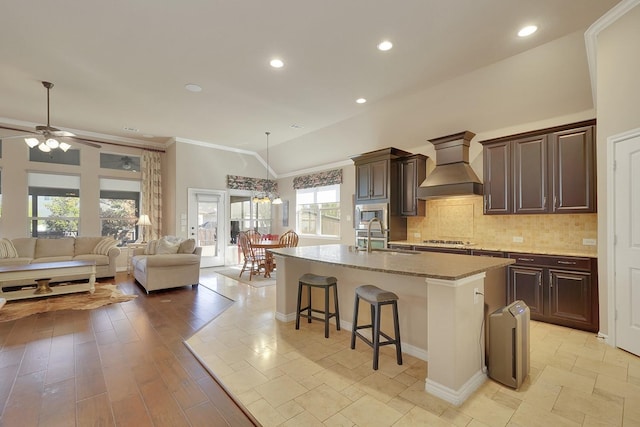 kitchen featuring tasteful backsplash, appliances with stainless steel finishes, a breakfast bar, custom exhaust hood, and a sink