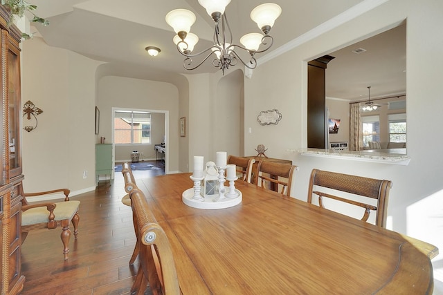 dining space with arched walkways, crown molding, visible vents, dark wood-style floors, and an inviting chandelier