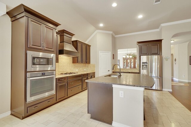 kitchen with a center island with sink, tasteful backsplash, appliances with stainless steel finishes, ornamental molding, and a sink