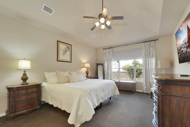 bedroom featuring dark carpet, baseboards, visible vents, and a raised ceiling