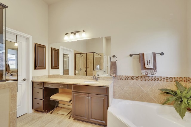 bathroom with a garden tub, a shower stall, wood finished floors, and vanity