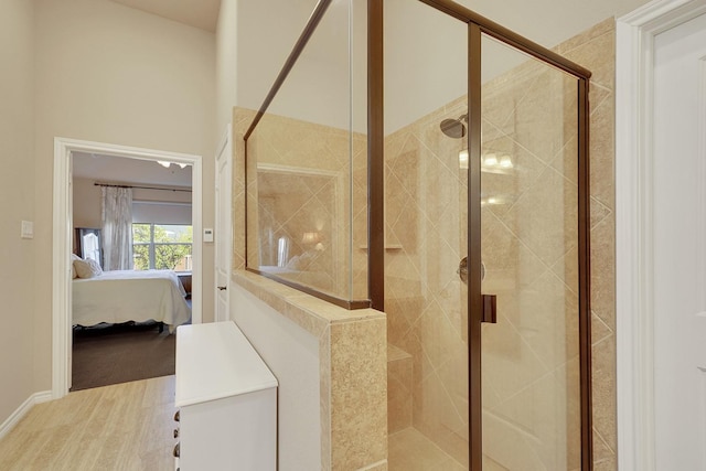 bathroom featuring wood finished floors, connected bathroom, and a shower stall