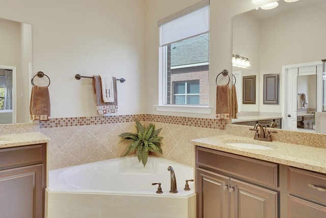 bathroom featuring a bath, two vanities, and a sink