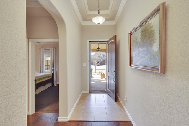 doorway with arched walkways, light wood-style floors, plenty of natural light, and crown molding