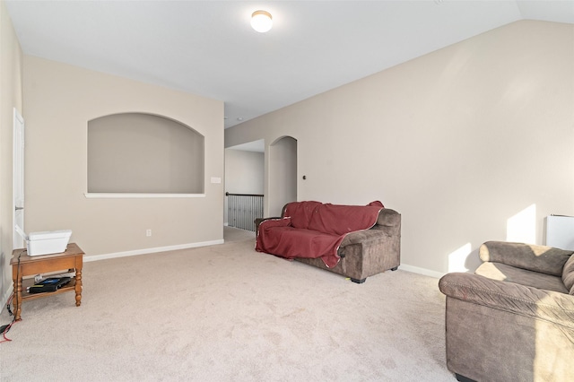 living area with arched walkways, baseboards, carpet flooring, and lofted ceiling