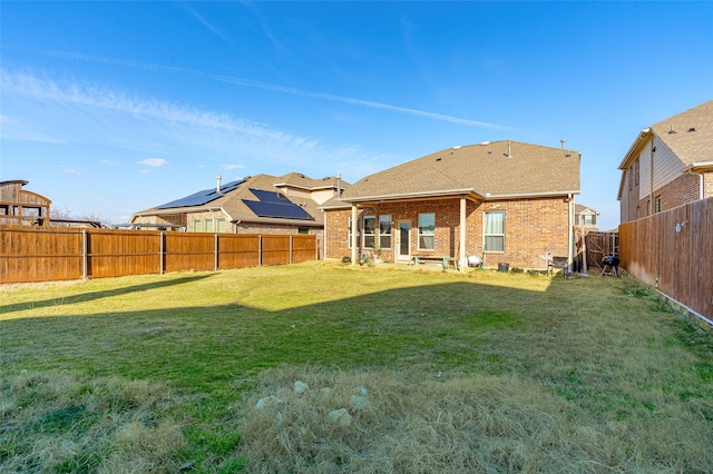 rear view of property with brick siding, a lawn, and a fenced backyard