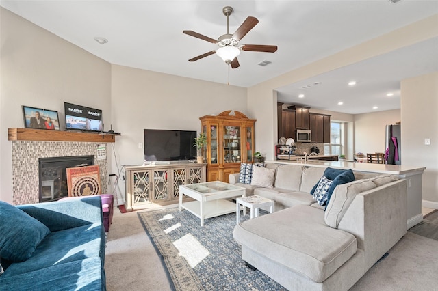 carpeted living area with ceiling fan, recessed lighting, visible vents, baseboards, and a glass covered fireplace