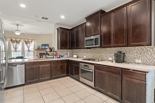 kitchen with light countertops, appliances with stainless steel finishes, a sink, and decorative backsplash