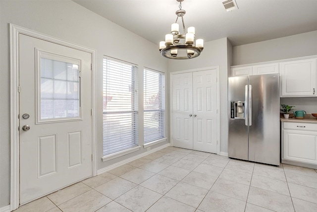 kitchen featuring a chandelier, decorative light fixtures, stainless steel fridge, light tile patterned floors, and white cabinets