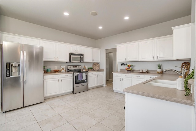 kitchen with appliances with stainless steel finishes, white cabinets, sink, and light tile patterned floors