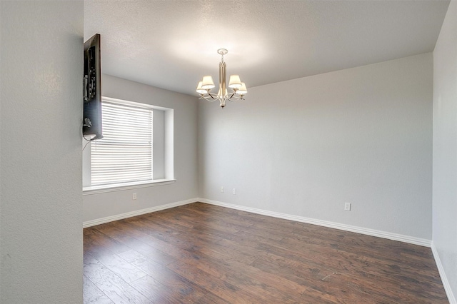 unfurnished room with a notable chandelier and dark wood-type flooring