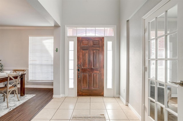 foyer featuring ornamental molding, light tile patterned flooring, and plenty of natural light