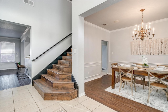 tiled dining space with ornamental molding and a chandelier