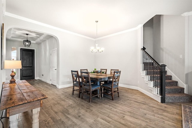 dining space with wood-type flooring, ornamental molding, and a chandelier