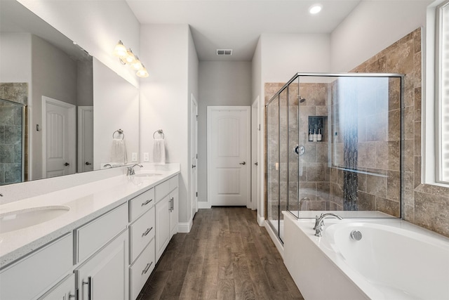 bathroom featuring hardwood / wood-style flooring, vanity, and plus walk in shower