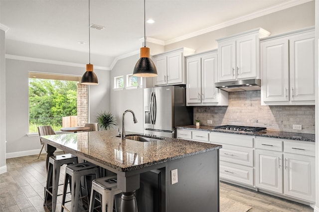 kitchen with pendant lighting, an island with sink, white cabinetry, appliances with stainless steel finishes, and sink