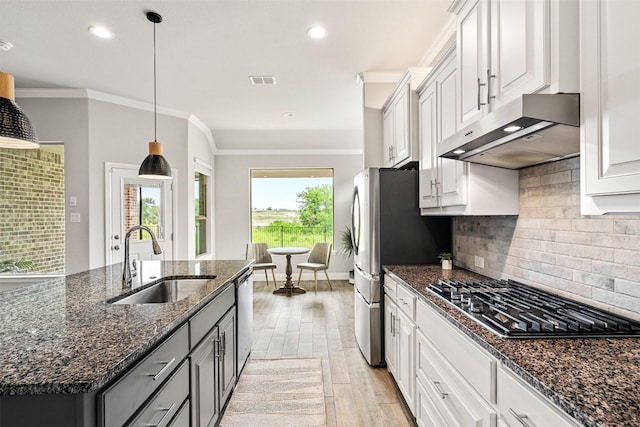 kitchen with white cabinets, dark stone countertops, a center island with sink, stainless steel appliances, and sink