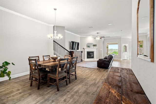14872 Gladstone Dr, Aledo, TX 76008 - dining room featuring wood finished floors, baseboards, ceiling fan with notable chandelier, a glass covered fireplace, and ornamental molding