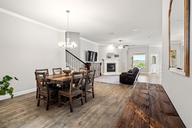 dining space featuring crown molding, ceiling fan with notable chandelier, and hardwood / wood-style floors