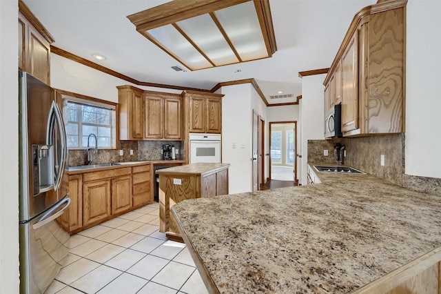 kitchen featuring sink, kitchen peninsula, a kitchen island, crown molding, and appliances with stainless steel finishes